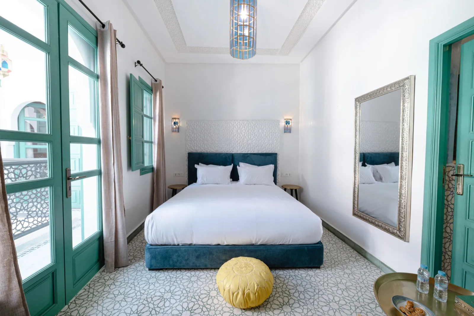 Chambre turquoise avec lit king-size et pouf doré