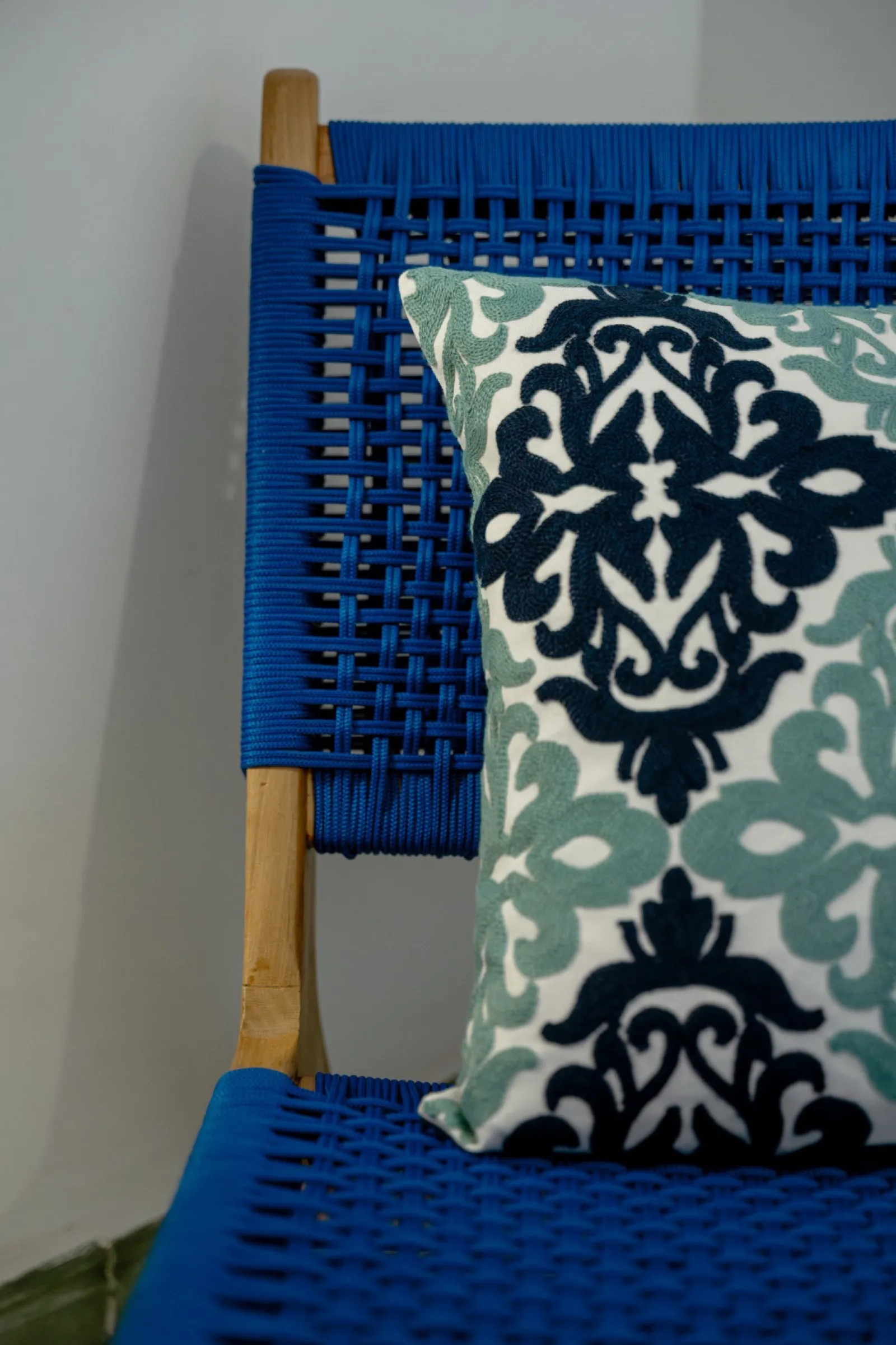Chaise tissée bleue et coussin brodé en gros plan